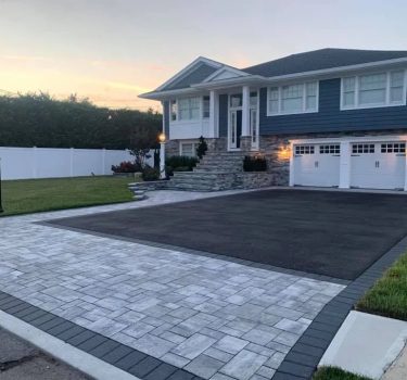 A modern two-story house with blue siding, stone accents, and a well-maintained yard, featuring a spacious driveway and mailbox.