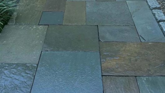A close-up view of a newly laid stone pathway, featuring various shades of slate tiles in a neat, interlocking pattern. A close-up view of a newly laid stone pathway, featuring various shades of slate tiles in a neat, interlocking pattern.