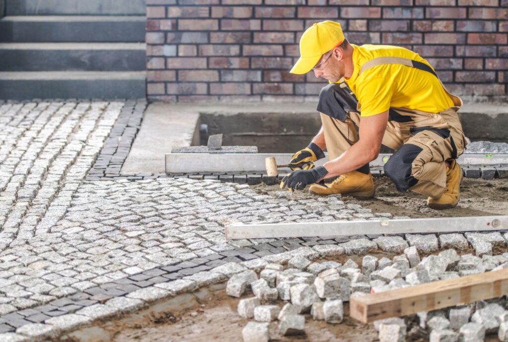 A stonework contractor lays pavers in a driveway.